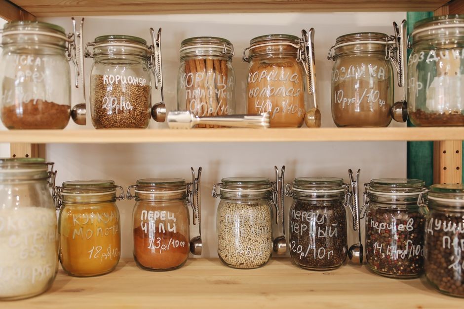 Glass jars of pantry ingredients arranged on a kitchen shelf.