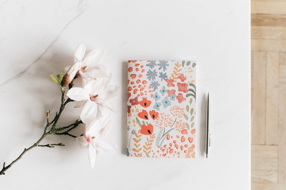 A floral reading notebook beside a delicate branch